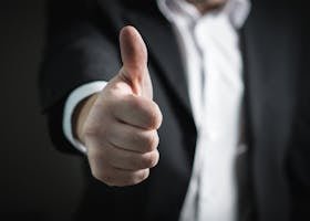 A close-up of a man's thumbs up gesture, symbolizing success and agreement.